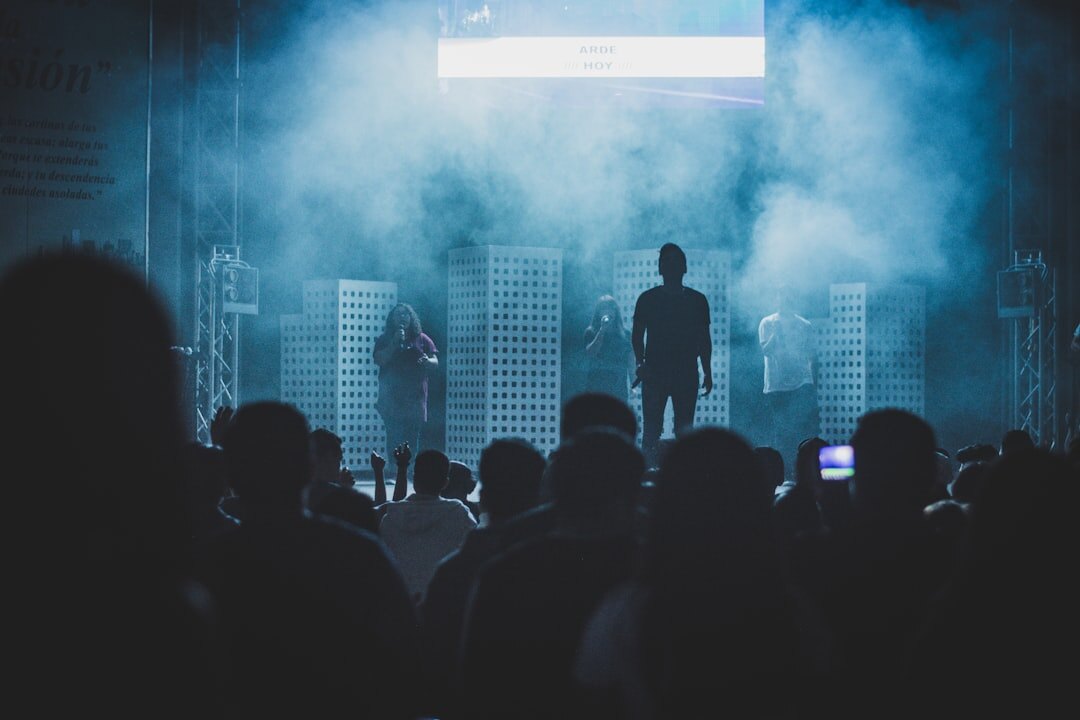 Audience silhouettes watching a speaker on a dark stage